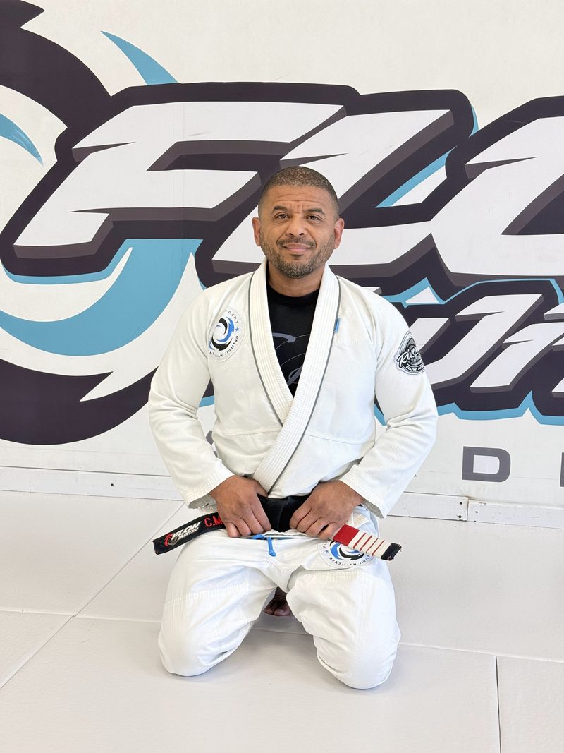 El Profesor Carlos Miller, cinturón negro 4.º grado, de rodillas en el tatami de Flow Academy Indio