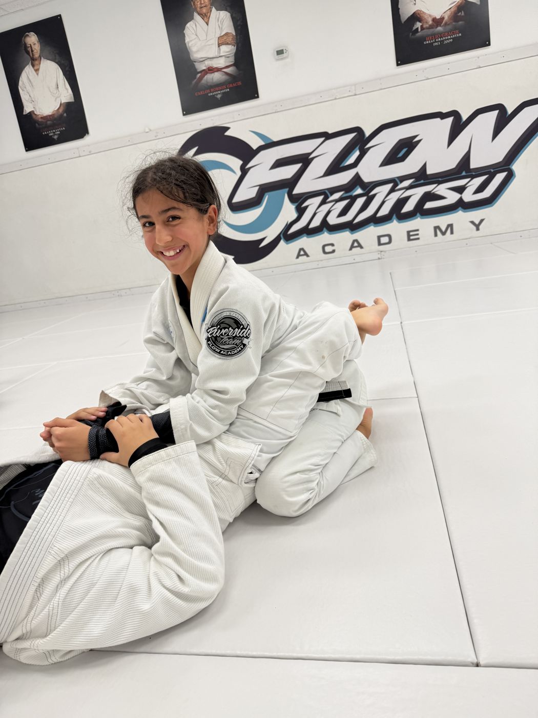 La misma alumna juvenil sonriendo a la cámara mientras mantiene la llave, con el logo turquesa de Flow atrás